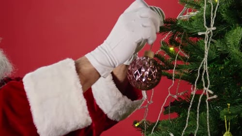 Hands of Santa Claus Decorating Fir Tree on Christmas Eve