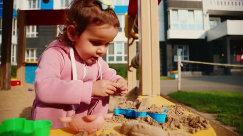 Un jeune enfant s'engage dans un jeu créatif avec des jouets de sable dans un environnement de bac à sable coloré en appréciant