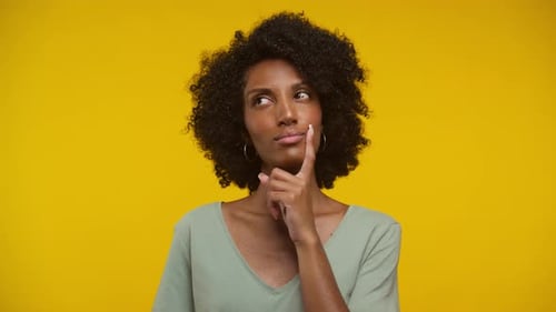 Thoughtful Woman Ponders Decisions Against Yellow Backdrop