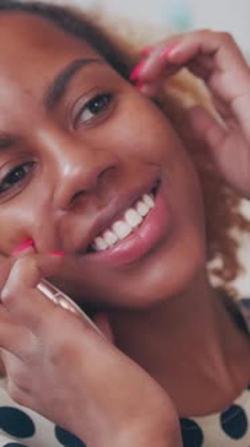 Une femme souriante parle au téléphone dans un cadre intérieur lumineux