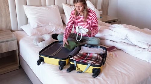 Woman Packing Suitcase on Bed for Vacation