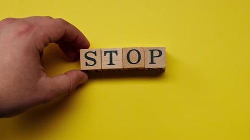 um fundo amarelo quente sem sombras, o homem colocou cubos de madeira à mão com palavras coloridas dispostas