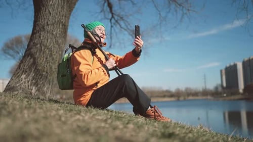 Greyhaired Woman in Activewear Taking Selfie on Shore of Pond in City Park Healthy Lifestyle and