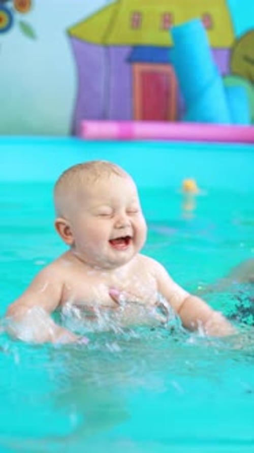 Smiling brunette woman holds a cute blond baby in the swimming pool.