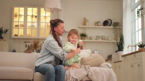 Woman and Baby Playing on Couch at Home