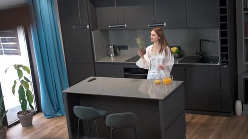 Woman Enjoys Juice and Pineapple at Kitchen Island