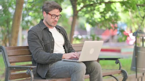 Man Working on Laptop in Green Urban Park