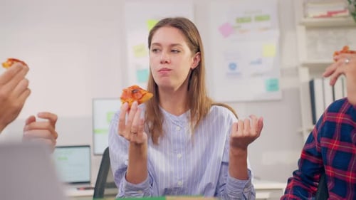Group of businessman and woman eat pizza while working in the office.