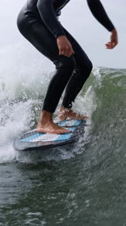A CloseUp Perspective of a Surfer Skillfully Riding a Wave While Balancing on a Surfboard in Dynamic