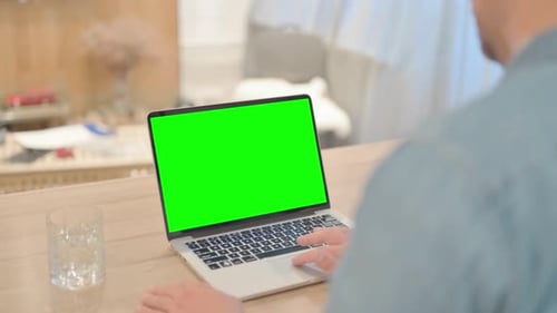 Young Man Using Laptop with Green Screen