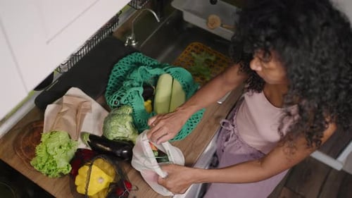 Mujer saca verduras de bolsas ecológicas reutilizables en la cocina después de comprar en la tienda