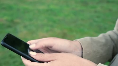 Nahaufnahme weiblicher Hände mit einem Smartphone, Naturhintergrund, Frau mit Handy bei Sonnenuntergang