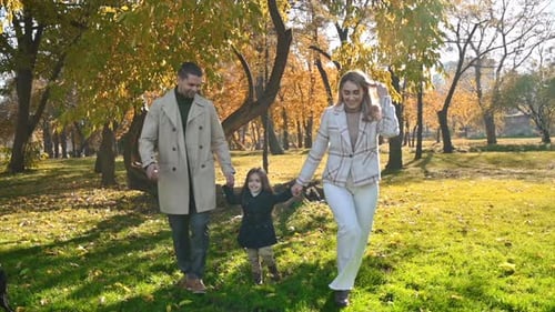 Happy family in an autumn park. Mother and father slowly running with daughter and their dog, yellow