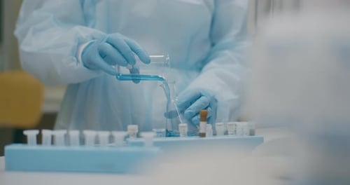 Lab Worker Mixing Liquids in Glass Beakers