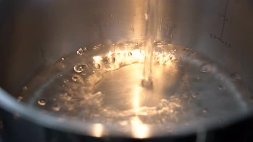 Water is Poured Into a Pot Closeup