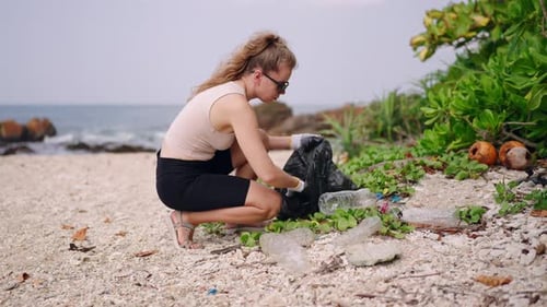 Un voluntario limpia una costa llena de basura recolectando desechos plásticos en bolsas enfocadas en mujeres que limpian la costa ecológica