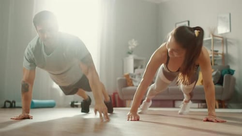 Athletic Couple Doing Push-Ups Together in Living Room