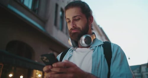Man Smiling Using Smartphone on City Street