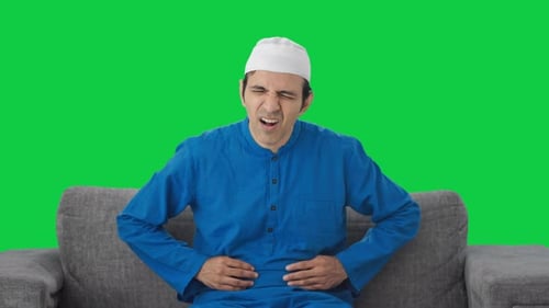Sick Muslim man suffering stomach pain Green screen