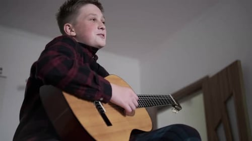 Teen Playing Guitar and Singing in Bedroom