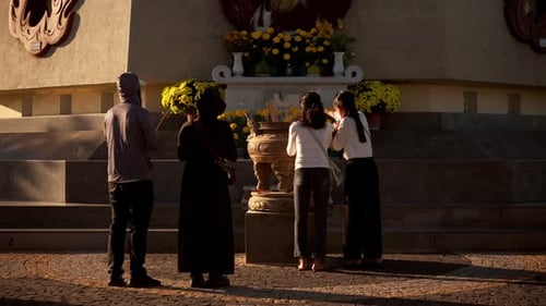 Vue arrière de quatre personnes méconnaissables debout devant un Bouddha priant pour la santé et
