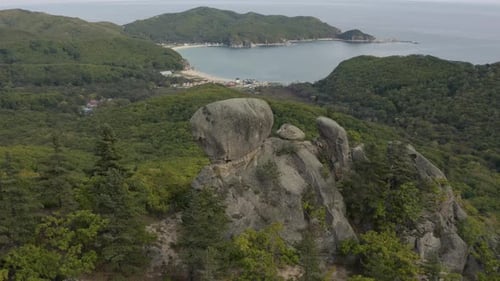Vue aérienne en pivot lent autour d'une ancienne formation de pierres mégalithiques au sommet d'une montagne boisée