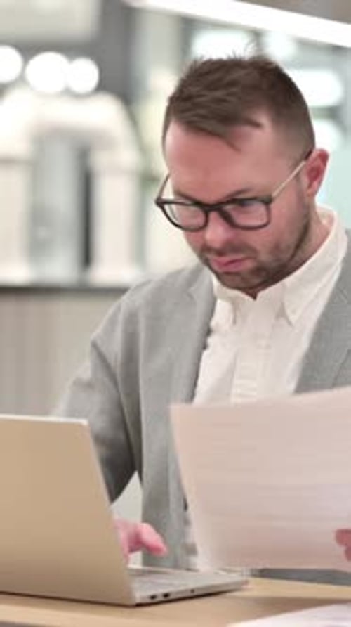 Professional Man Working at Laptop with Documents in Office