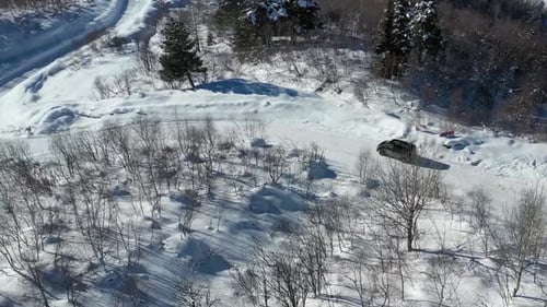 Gorgeous aerial footage of a black van driving on a road covered in snow, 4k