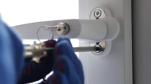 Hands Tightening Window Security with Screwdriver