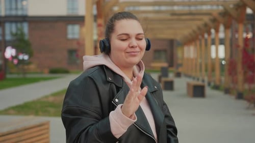Lady Dancing in Headphones Enjoying Music with Wooden Structures Behind