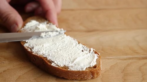 Spreading Cream Cheese on Brown Bread Slice