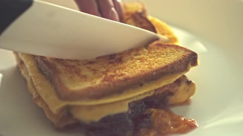Person Cuts Grilled Cheese and Fruit Sandwich