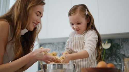 Woman and Girl Mixing Dough in Kitchen Together