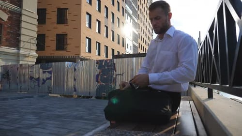 Young Businessman Sits Down on Bench at Urban Street and Takes Out Laptop of Briefcase Entrepreneur