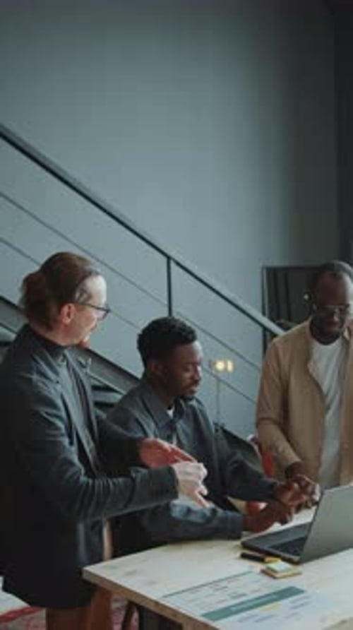 Businessman Discussing Data On Laptop with Two Colleagues in Office