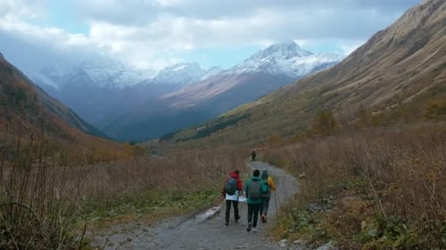 Rückansicht einer Gruppe von Touristen, die eine Schlucht zwischen großen Berghängen erkunden