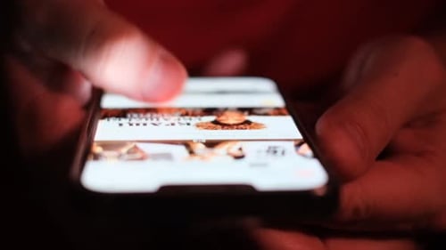 Close up Hand Scrolling Mobile Phone at Night