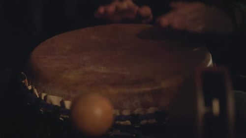 Un batteur méconnaissable jouant des tambours Djembé en gros plan