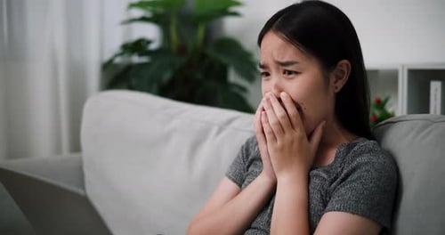 A young woman shows a surprised expression while looks at laptop.