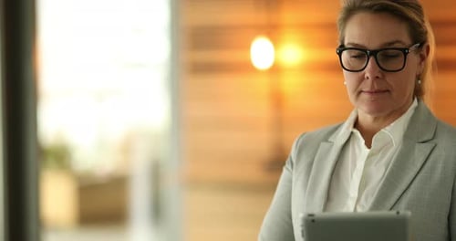 Focused Mature Businesswoman Standing in the Hallway of a Modern Office Working