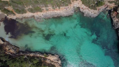 Aerial top down view over beautiful turquoise waters in Mallorca rocky coastline