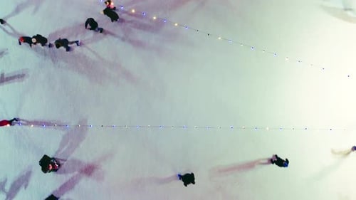 Menschen, die auf der Eisbahn Schlittschuhlaufen, im Freien, Winternacht, Ansicht von oben