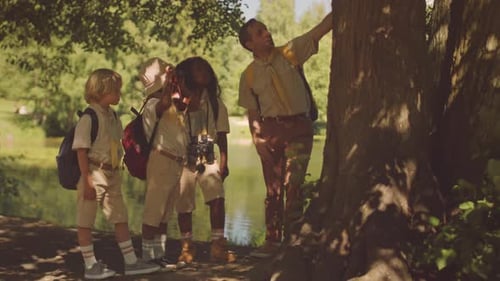 Teacher with Cub Scouts Chatting under Tree in Forest
