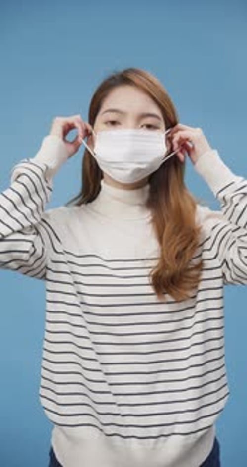 Young Woman Puts on Protective White Medical Mask