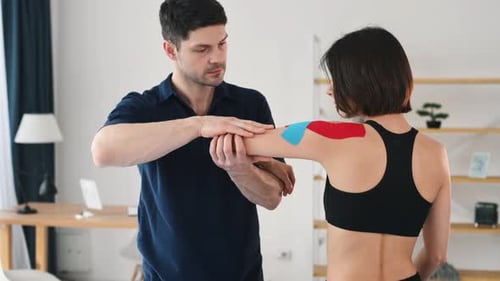 Man Massaging Woman's Arm with Red and Blue Tape