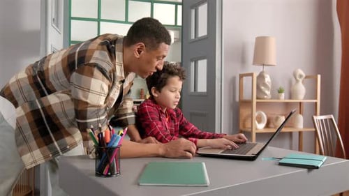 Father Helping Son with Laptop at Home
