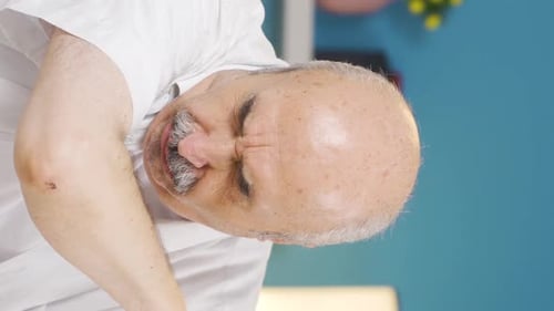 Vertical video of The sick old man can't stop coughing.