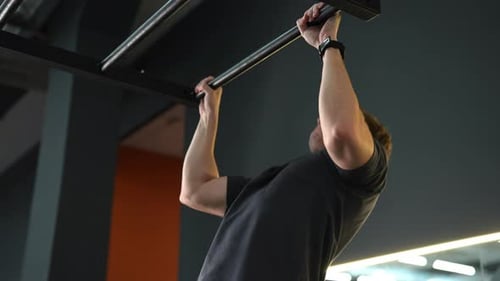 Tilt Up Shot of Beginner Sportsman Doing Pullups on Horizontal Bar at Gym Sports Male Workout