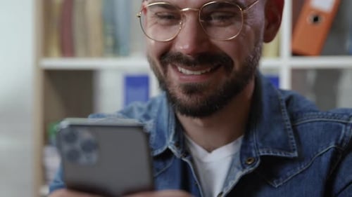 Man Using Smartphone Indoors Smiling at Office