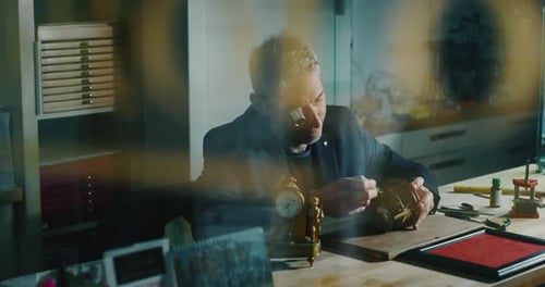 Slow motion close up of a professional watchmaker repairer working on a vintage mechanism clock in